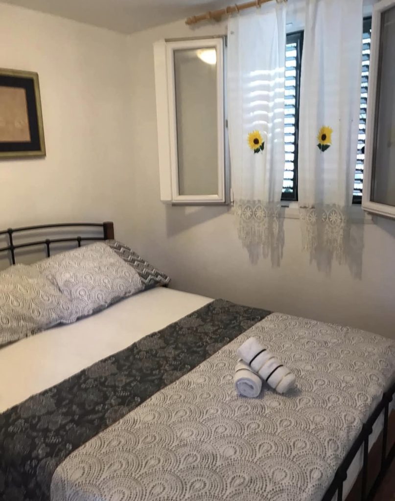 Spalnica z zakonsko posteljo in svetlim oknom v robinzonski hišici